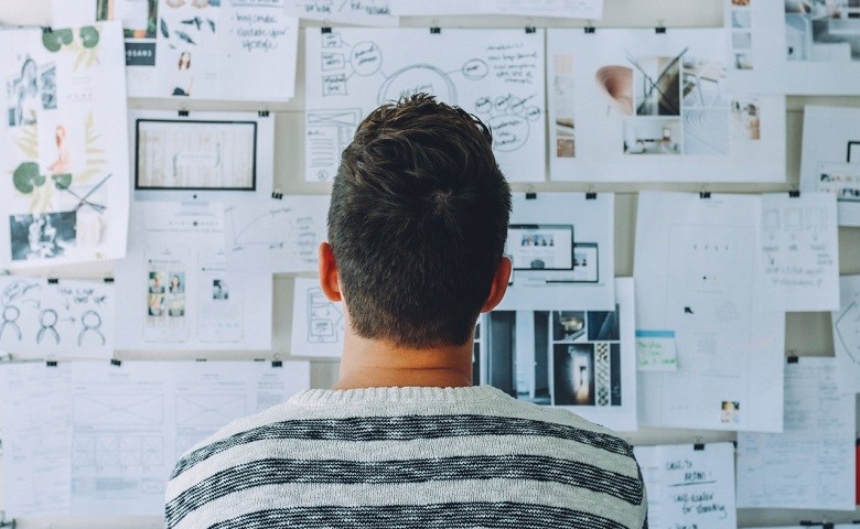 man looking at papers on wall